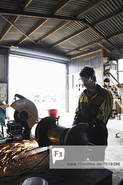 Metal worker using grinder in shop