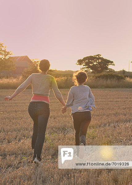 Mother and daughter running in field