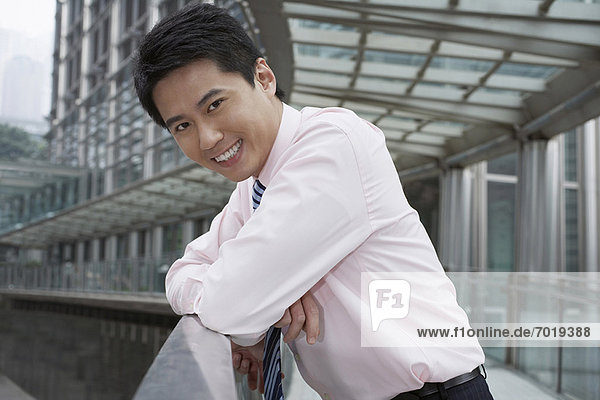 Smiling businessman leaning on banister