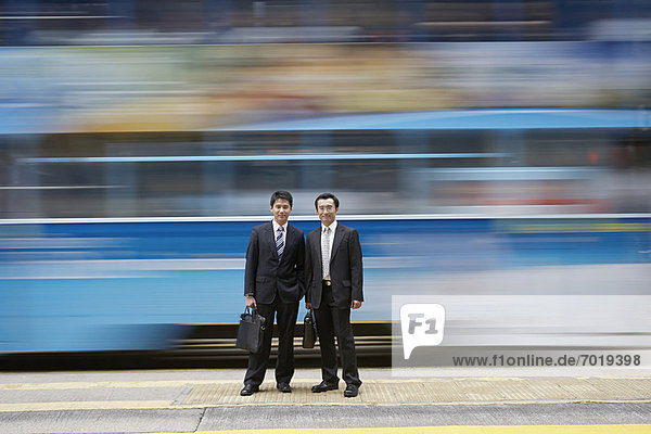 Businessmen standing by blurred bus