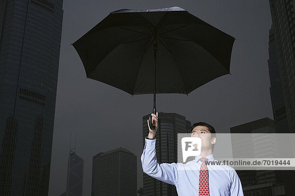 Businessman with umbrella on city street