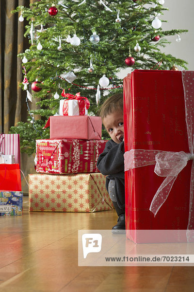 Kleines Mädchen versteckt sich hinter einem Weihnachtsgeschenk