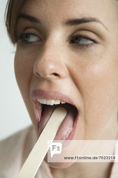 Junge Frau mit Munduntersuchung mit Zungenspatel