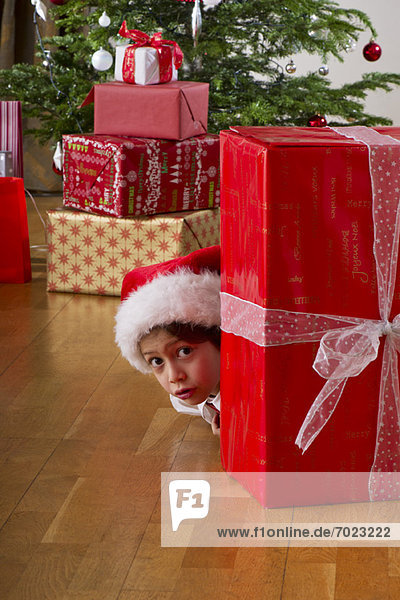 Junge versteckt sich hinter einem Weihnachtsgeschenk