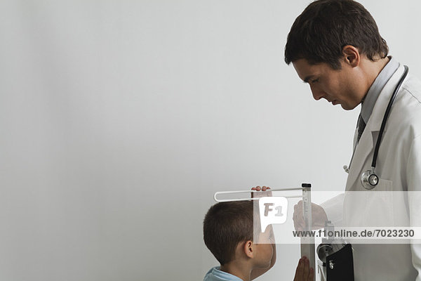 Arzt beim Messen des kleinen Jungen während der Untersuchung