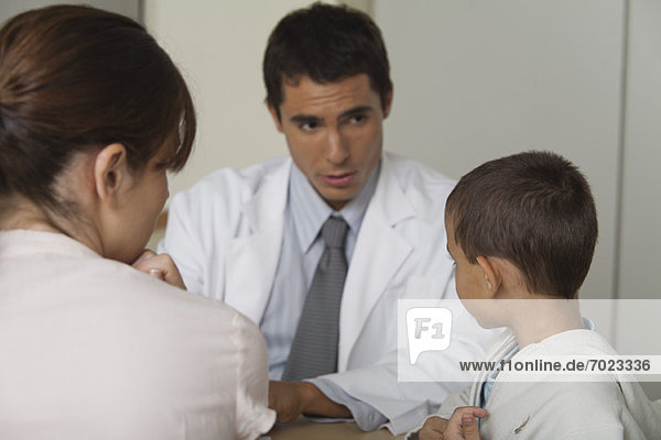 Arzt im Gespräch mit kleinem Jungen und Frau