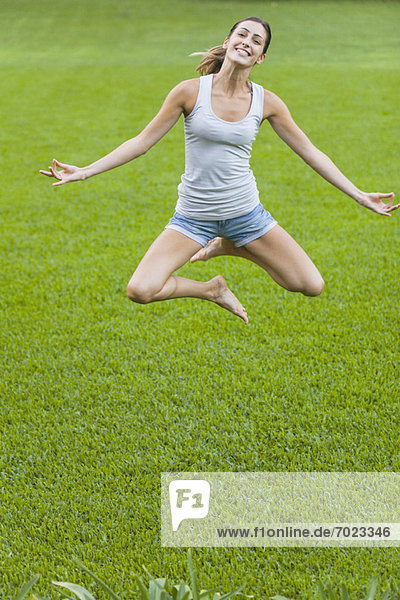 Junge Frau beim Springen in der Luft in Yogastellung