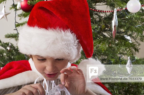 Boy wearing Santa hat  opening Christmas present