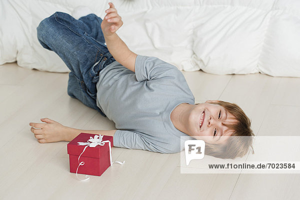 Junge auf dem Boden neben der Geschenkbox liegend