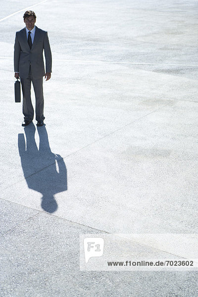 Businessman standing outdoors with briefcase in hand