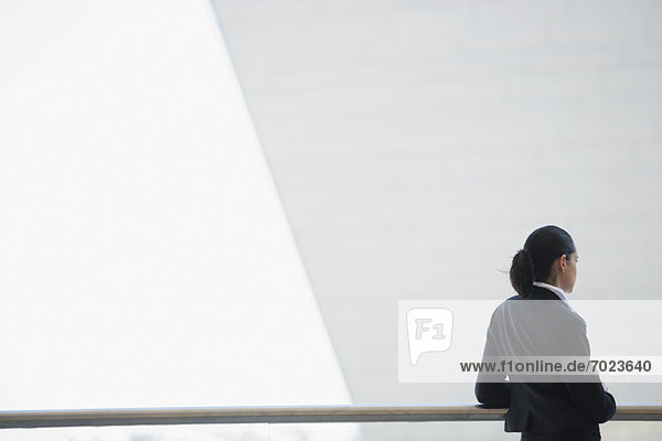 Businesswoman leaning against railing  looking away in thought