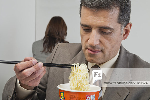 Businessman eating ramen noodles in office