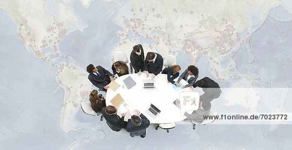 Business executives meeting on top of superimposed world map