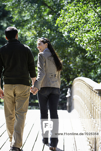 Couple walking on footbridge (rear view)