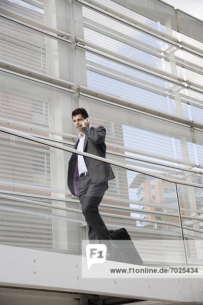 Businessman with suitcase talking on cell phone (low angle view)