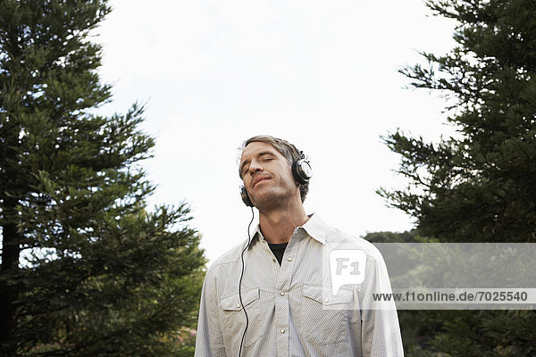 Mid adult man listening to headphones