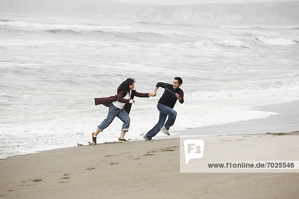 Young couple running on sandy beach