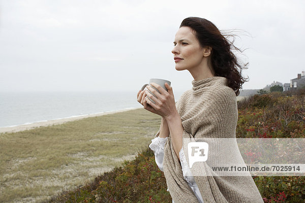 Young woman drinking coffee at beach