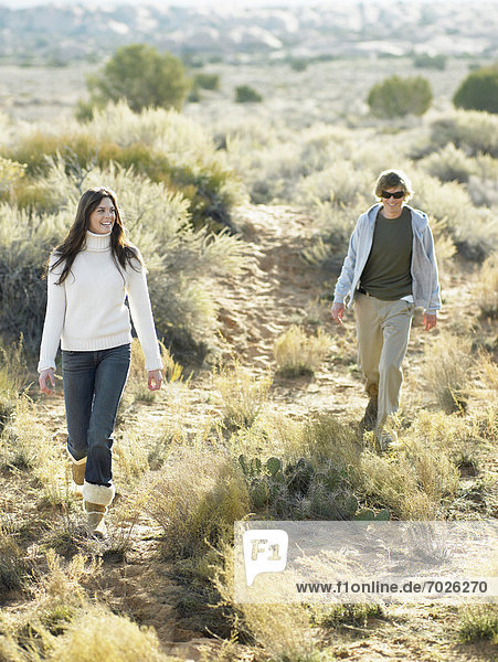 Young couple walking on shrubs