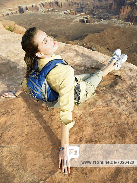 Young woman with backpack sitting on cliff  high angle view  rear view
