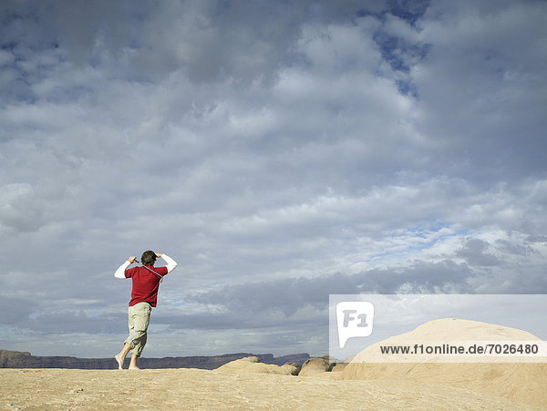 Man playing golf at rock strata