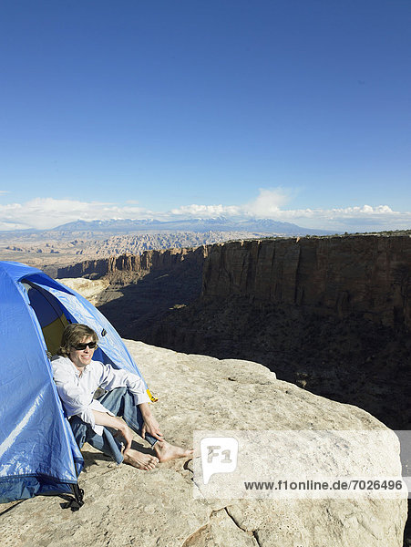 Young man sitting in tent by cliff  high angle view  Moab  Utah  USA