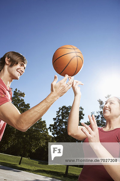 Woman and man spinning basketball on finger