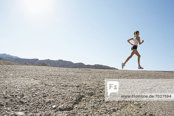 Young woman jogging in rocky landscape (low angle view)