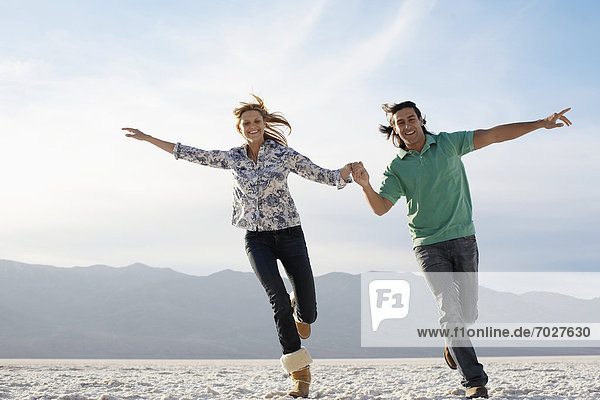 Couple running with arms outstretched