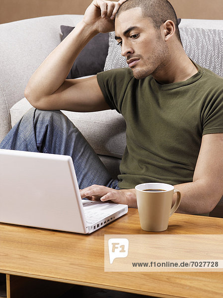 Young man using laptop on coffee table