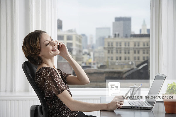 Businesswoman talking on the phone at desk