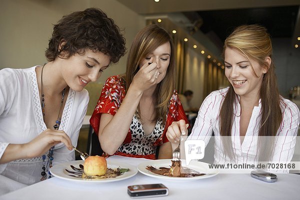 Teenage girls eating deserts in restaurant