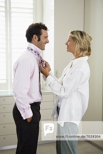 Woman tying necktie for husband
