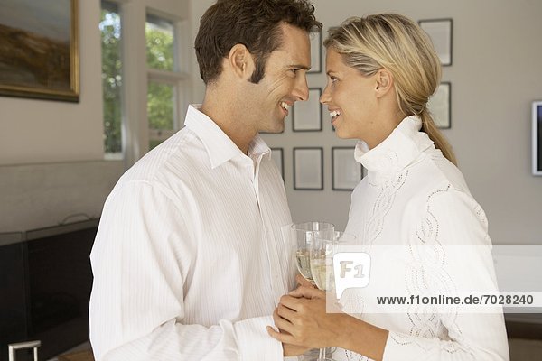 Mid adult couple holding hands and drinking champagne