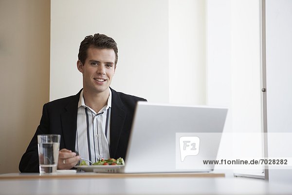 Businessman with laptop eating salad