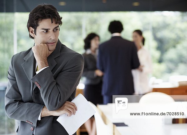Businessman with documents thinking  colleagues in background