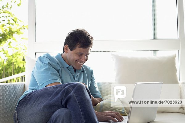 Mature man using laptop on sofa