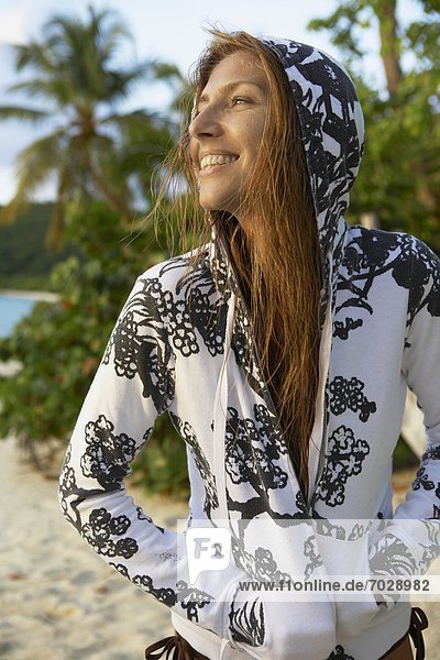 Mid adult woman in hooded top on beach