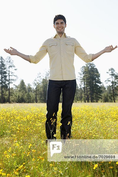 Young man standing in a field of wildflowers