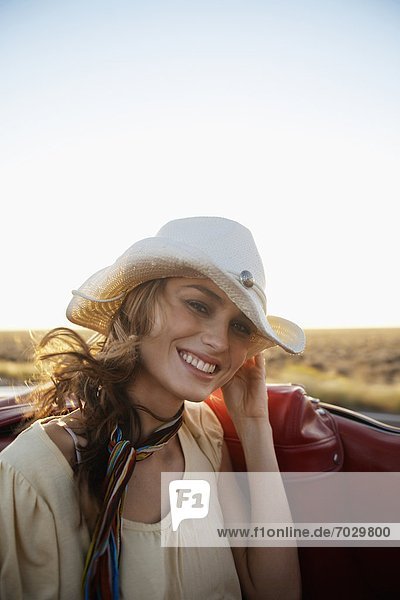 Young woman in cowboy hat traveling in convertible