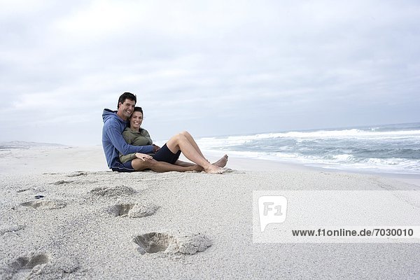 Mid adult couple sitting on sandy beach  Cape Town  South Africa