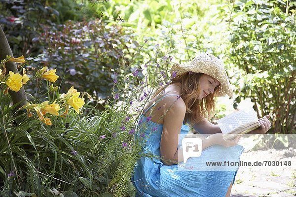 Young woman reading book by flowers
