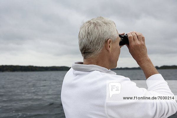 Mature man looking through binoculars