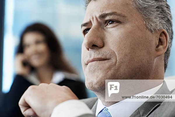 Businessman Thinking  Woman on Phone in Background