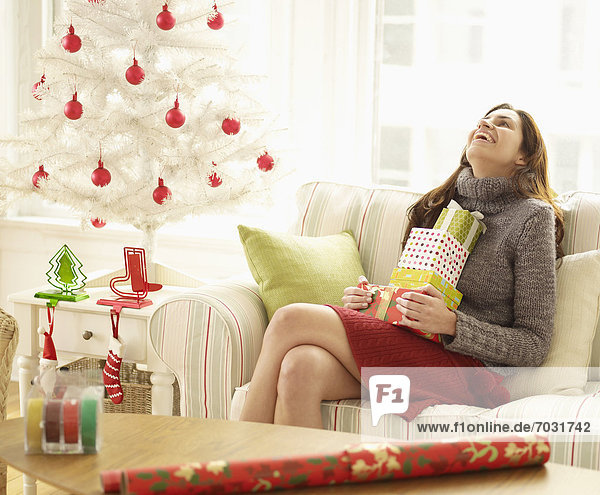 Mid-Adult Woman with Stack of Christmas Presents Laughing