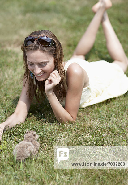 Mid-Adult Woman Looking at Rabbit on Lawn