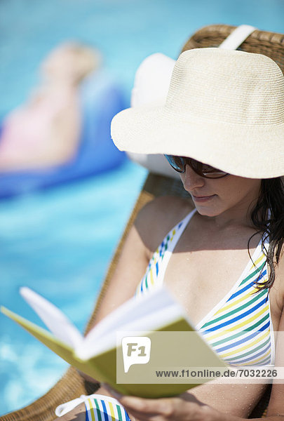 Mid-Adult Woman Reading Book by Pool