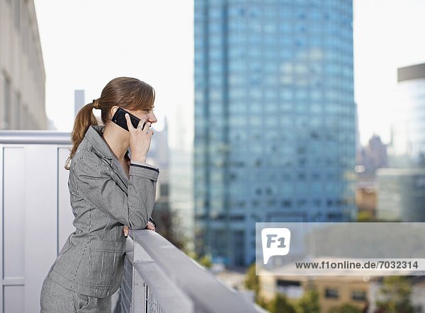 Businesswoman Using Cell Phone on Balcony