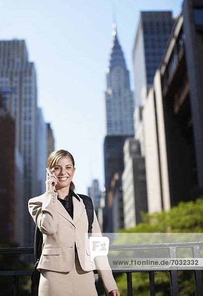 Mid-Adult Businesswoman on Cell Phone by Skyscrapers