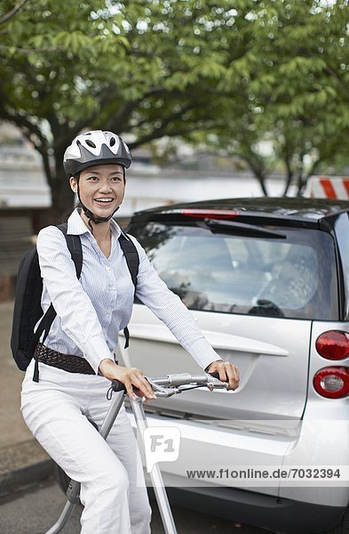 Mid-Adult Woman on Bicycle Beside Smart Car